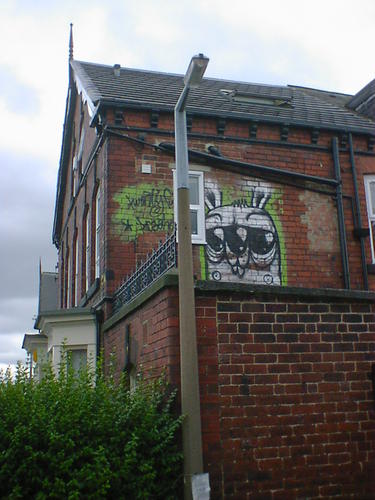 Green rabbit graffiti, on the upper storey of a red-brick terraced house.