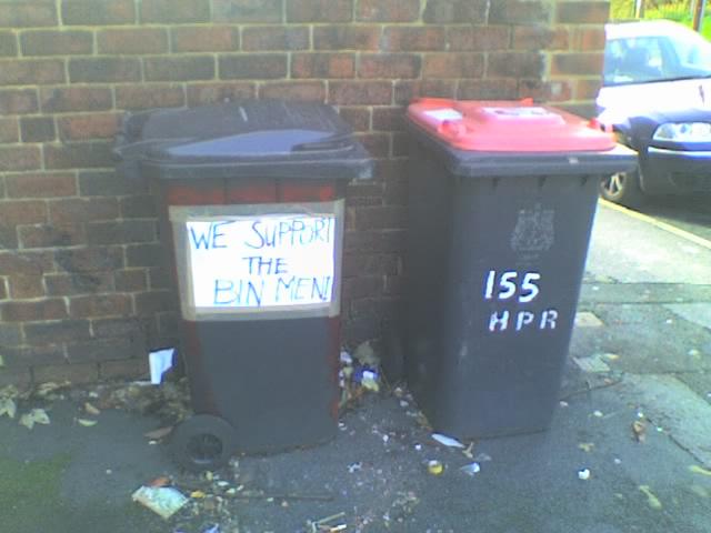 a sign affixed to a wheelie bin declares: we support the bin men