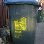 Wheelie bin with stencil art of a mob uprising, advertising Attila Bike Parts.
