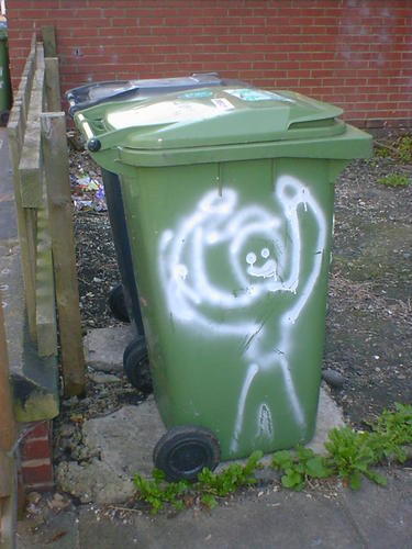 A grinning man painted on a wheelie bin, holding his arms high in victory.