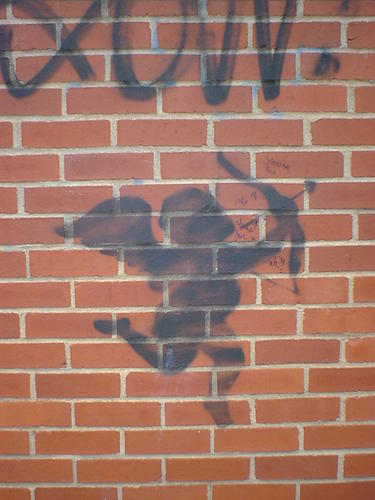 Silhouette of Cupid with bow, stencilled on a brick wall