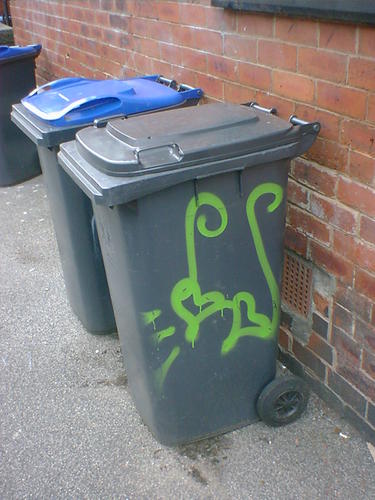 A wheelie bin with green hearts painted on.