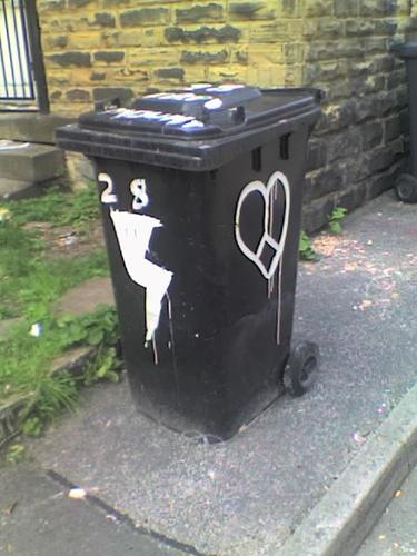 A wheelie bin painted with a lightning bolt on one side and a heart on another.