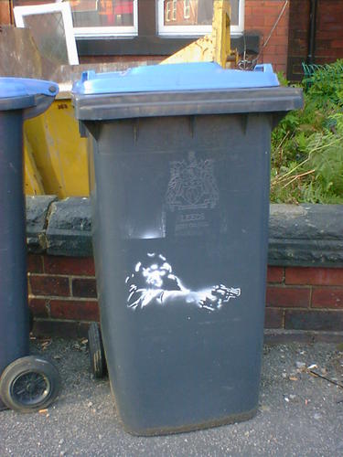 Stencil art on a wheelie bin. A monkey aiming a revolver, cop-show style.