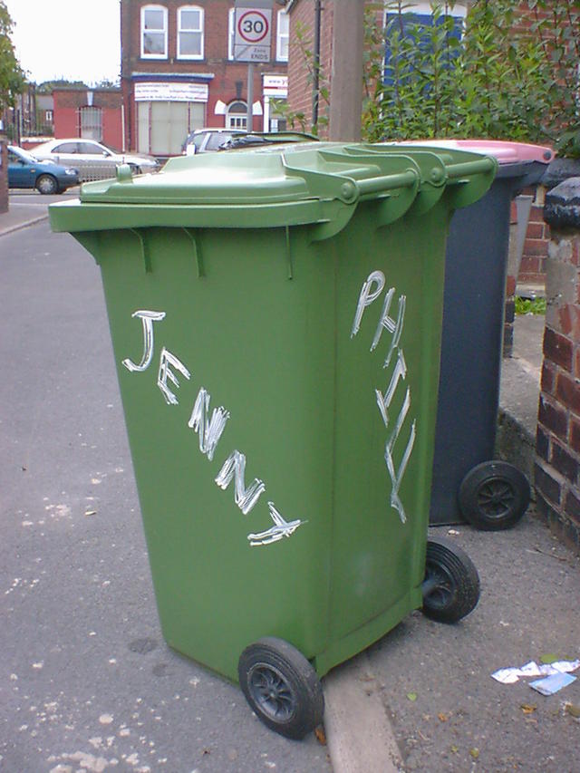 Jenny & Phill Green wheelie bin with Jenny and Phill daubed on two sides with white paint.