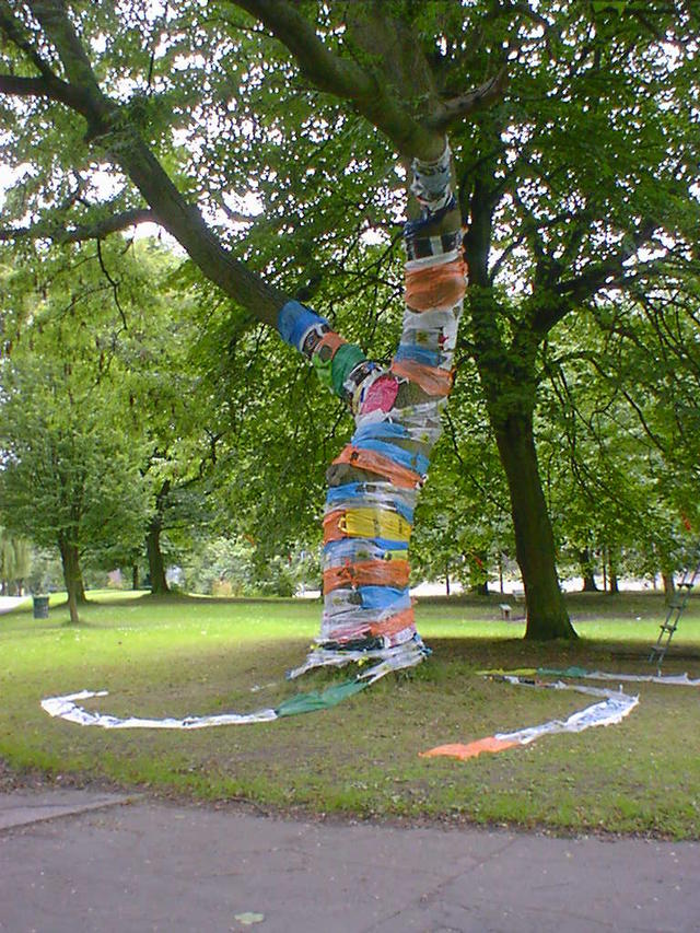 Tree trunk wrapped in plastic carrier bags.