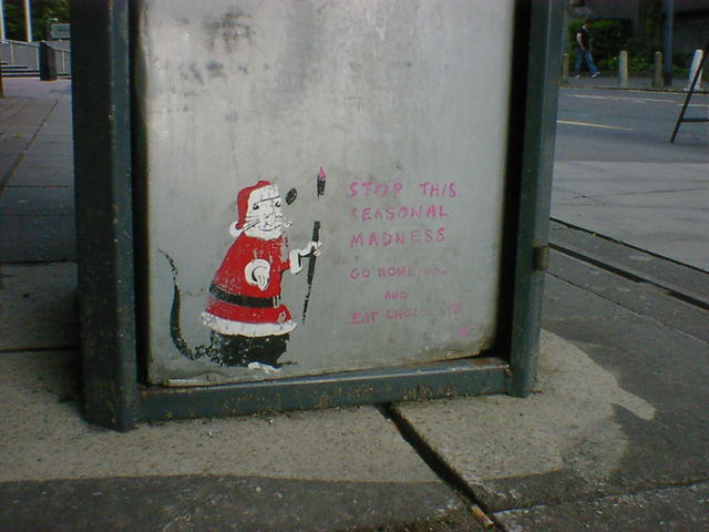 Small painting of a rat, dressed as Santa, at the base of a dustbin in Leeds.