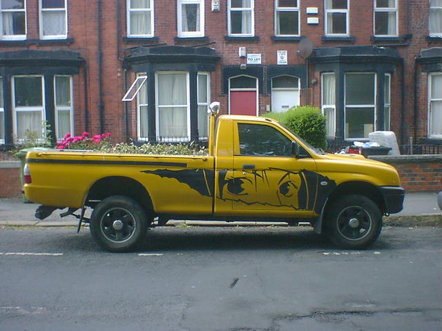 Yellow pickup truck with  Manga-style girl's eyes, painted on the side 