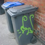 A wheelie bin with green hearts painted on.