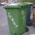 Green wheelie bin with Jenny and Phill daubed on two sides with white paint. 