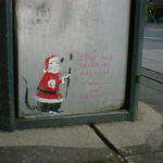 Small painting of a rat, dressed as Santa, at the base of a dustbin in Leeds.