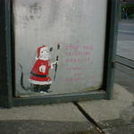 Small painting of a rat, dressed as Santa, at the base of a dustbin in Leeds.