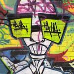 Graffiti art - a bald scientist with big green spectacles. The lenses say HA HA.