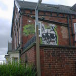 Green rabbit graffiti, on the upper storey of a red-brick terraced house.